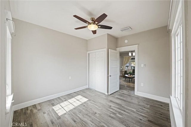 unfurnished bedroom with wood-type flooring, a closet, and ceiling fan