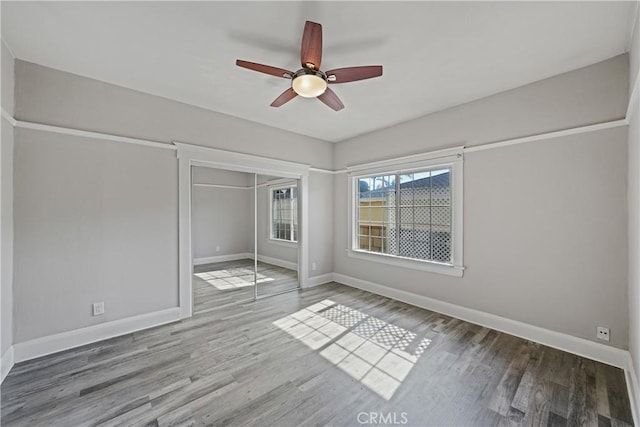 unfurnished bedroom with ceiling fan, wood-type flooring, and a closet