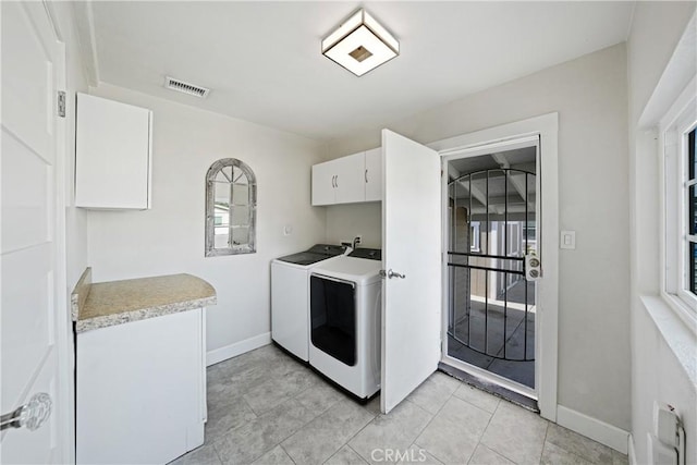 laundry room with cabinets, light tile patterned flooring, and washer and clothes dryer