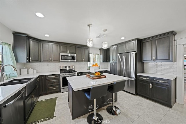 kitchen featuring a kitchen island, pendant lighting, sink, a breakfast bar area, and stainless steel appliances