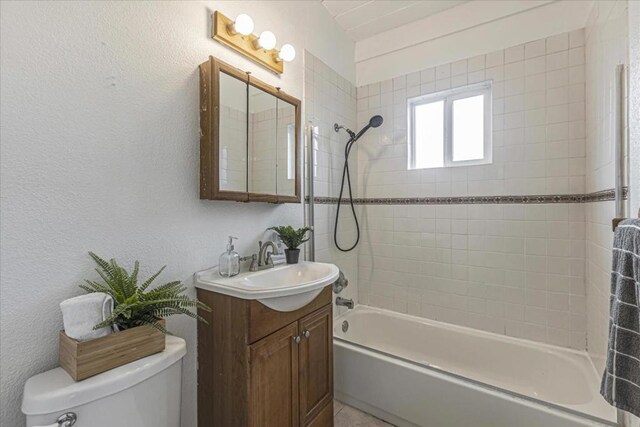 full bathroom with tiled shower / bath, vanity, and toilet