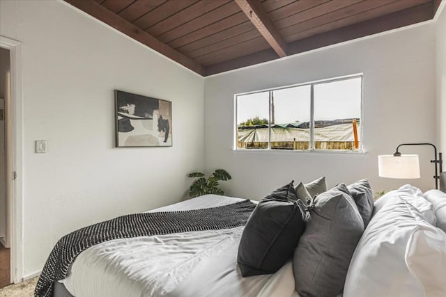 bedroom with beamed ceiling, carpet floors, and wooden ceiling