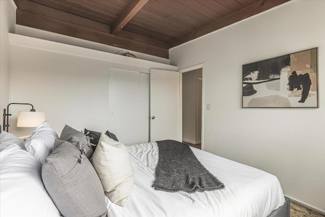 bedroom with beamed ceiling, wooden ceiling, and a closet