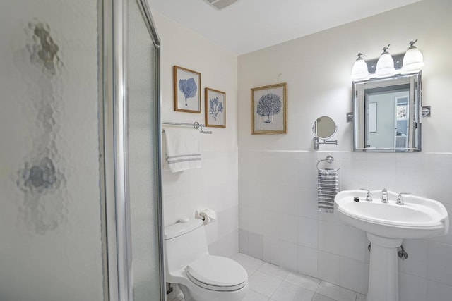 bathroom with tile walls, sink, tile patterned flooring, and toilet