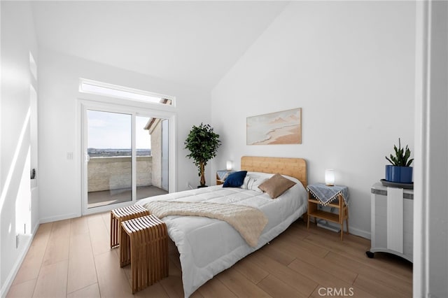 bedroom featuring access to exterior, high vaulted ceiling, and light wood-type flooring