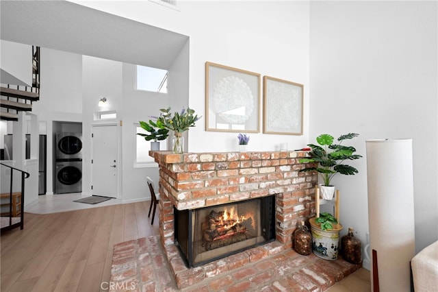 details featuring a brick fireplace, wood-type flooring, and stacked washing maching and dryer