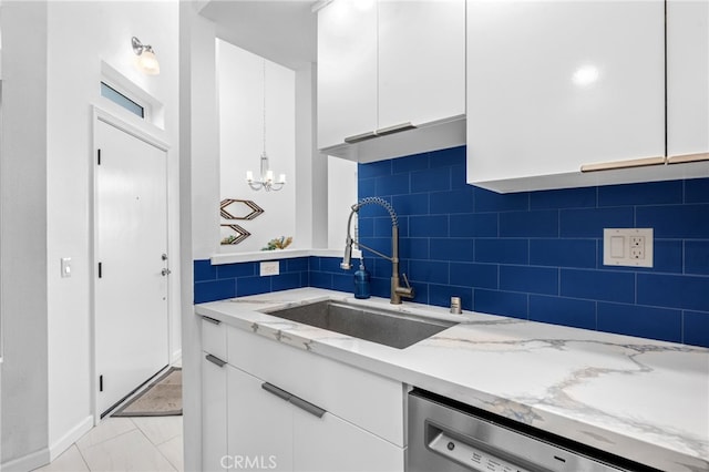 kitchen with white cabinetry, sink, dishwashing machine, and decorative backsplash