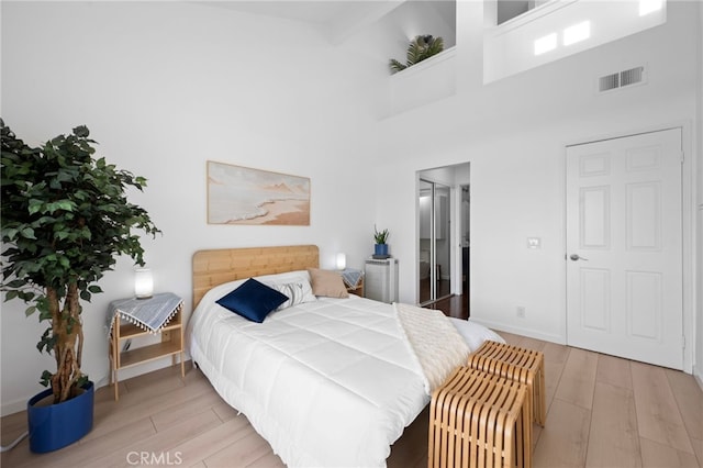 bedroom with a towering ceiling and light wood-type flooring