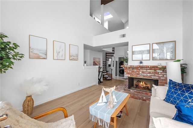 living room featuring hardwood / wood-style flooring, a brick fireplace, and a high ceiling