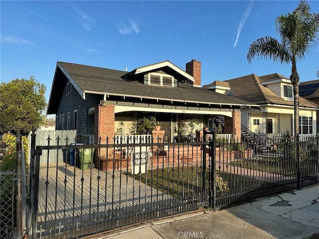 view of front facade featuring a fenced front yard, a gate, brick siding, and a chimney