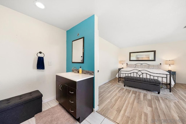 bedroom with lofted ceiling, sink, and light hardwood / wood-style floors