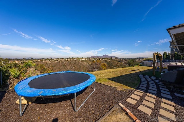 view of yard featuring a trampoline and a mountain view