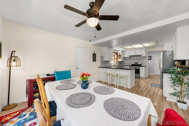 dining area featuring ceiling fan, sink, and light wood-type flooring