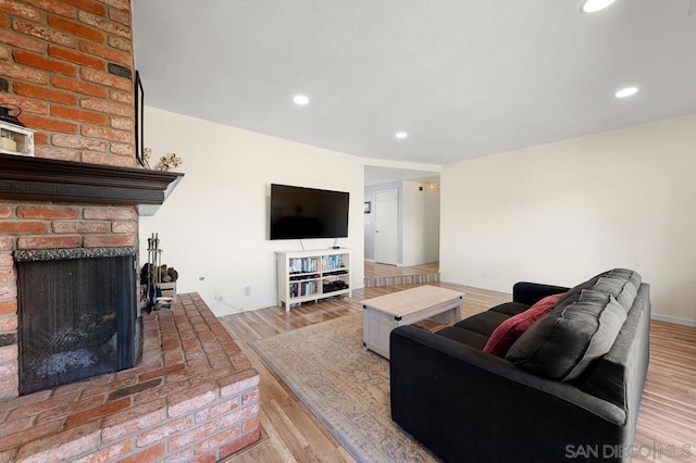 living room with wood-type flooring and a brick fireplace