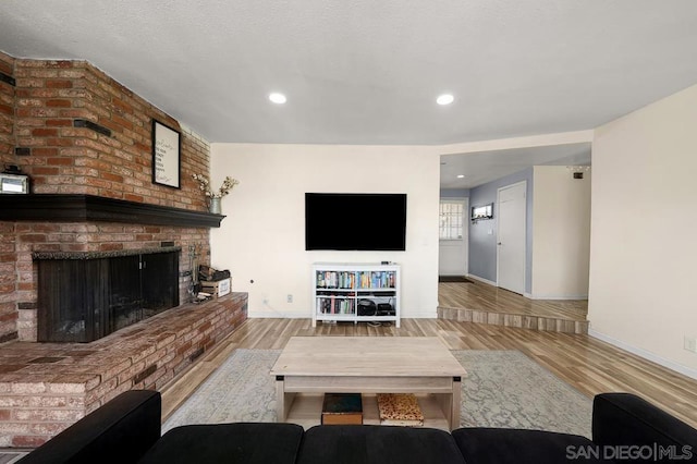 living room with a brick fireplace and light hardwood / wood-style floors