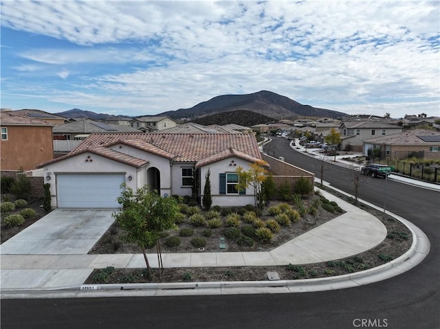 mediterranean / spanish-style house with driveway, a residential view, a tiled roof, a mountain view, and stucco siding