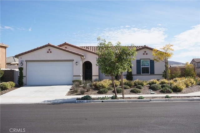 mediterranean / spanish-style house featuring a garage, driveway, a tiled roof, and stucco siding