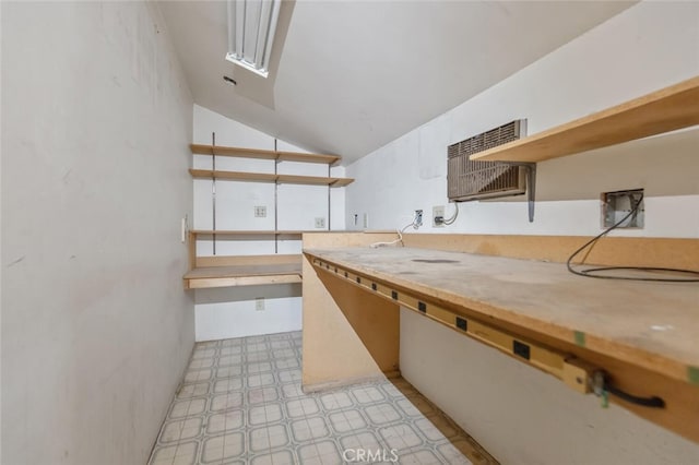 kitchen with lofted ceiling, an AC wall unit, and white cabinets