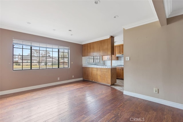 kitchen featuring crown molding, hardwood / wood-style flooring, tasteful backsplash, and kitchen peninsula