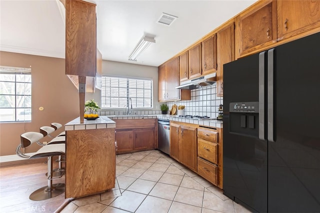 kitchen with tile countertops, sink, decorative backsplash, kitchen peninsula, and stainless steel appliances