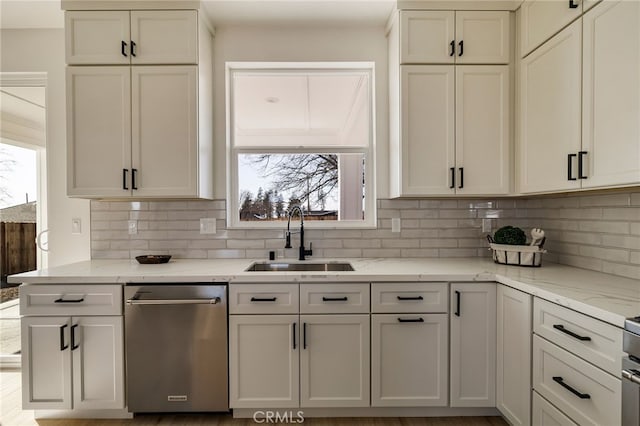 kitchen with light stone counters, stainless steel dishwasher, sink, and decorative backsplash