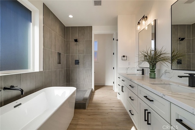 bathroom featuring independent shower and bath, vanity, wood-type flooring, and tile walls