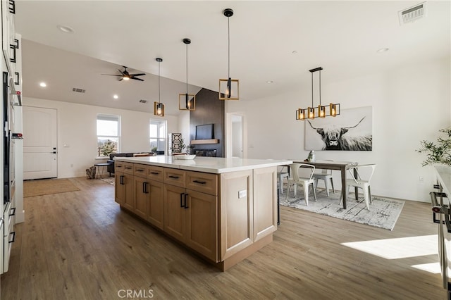 kitchen with a kitchen island, light hardwood / wood-style flooring, lofted ceiling, and decorative light fixtures