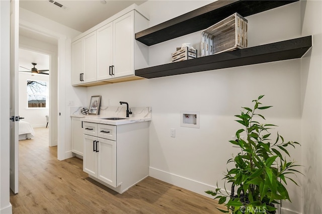 laundry room with sink, cabinets, light wood-type flooring, hookup for a washing machine, and ceiling fan