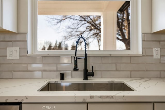 room details with light stone counters, sink, and tasteful backsplash