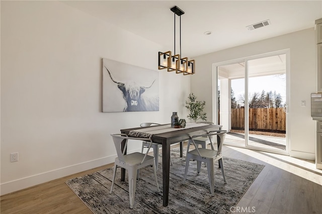 dining area featuring wood-type flooring and a notable chandelier