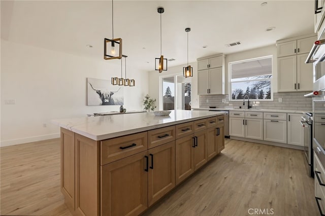 kitchen with stainless steel electric stove, tasteful backsplash, hanging light fixtures, a center island, and light hardwood / wood-style flooring