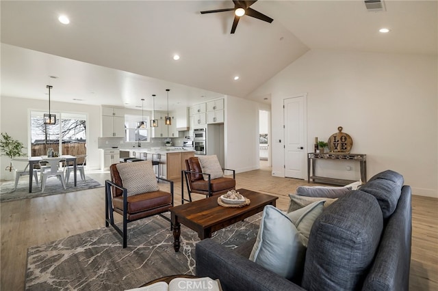 living room featuring lofted ceiling, ceiling fan, and light hardwood / wood-style flooring