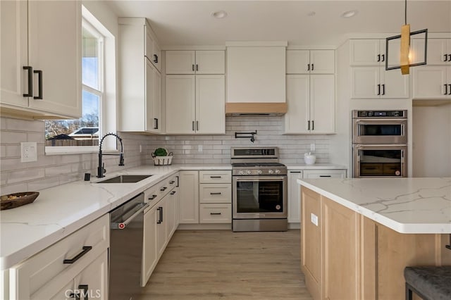 kitchen featuring light stone counters, decorative light fixtures, white cabinetry, and appliances with stainless steel finishes