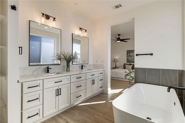 bathroom featuring vanity, hardwood / wood-style flooring, a tub, and ceiling fan