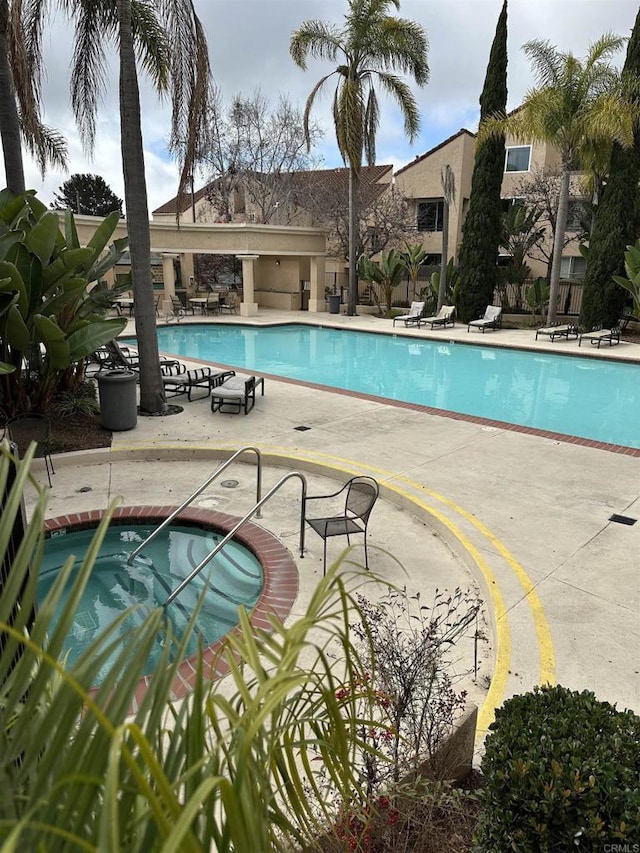 view of swimming pool featuring a community hot tub and a patio area