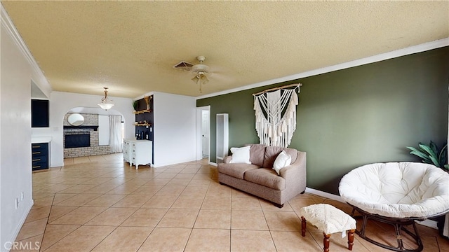 living room featuring ornamental molding, a brick fireplace, light tile patterned floors, and ceiling fan