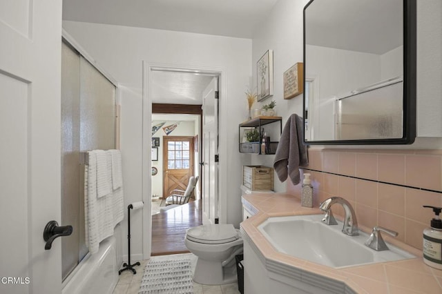 full bathroom with toilet, sink, enclosed tub / shower combo, tile patterned flooring, and backsplash