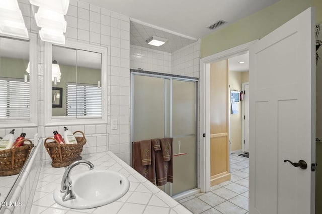 bathroom featuring tile patterned flooring, a shower with door, and tile walls