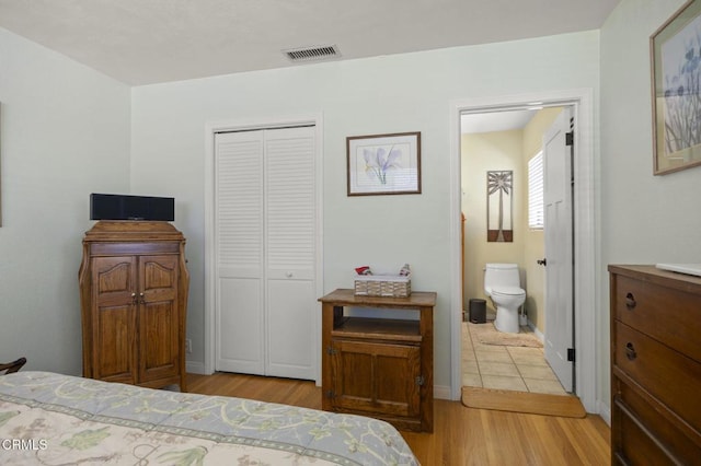 bedroom featuring connected bathroom, a closet, and light wood-type flooring