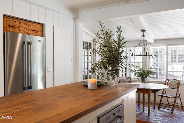 kitchen with butcher block countertops, beamed ceiling, hanging light fixtures, a notable chandelier, and high end fridge