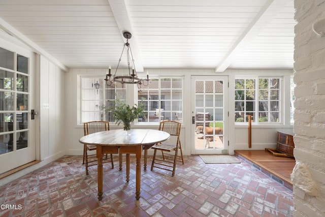 sunroom featuring beamed ceiling and a chandelier