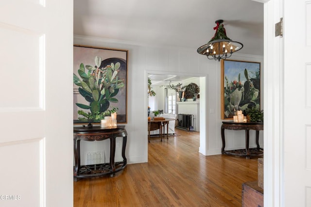 corridor with hardwood / wood-style floors, a notable chandelier, and ornamental molding