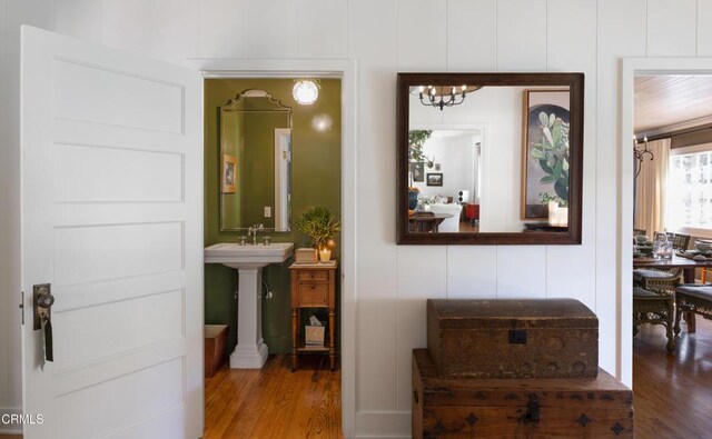 hall with wood-type flooring, a chandelier, and sink