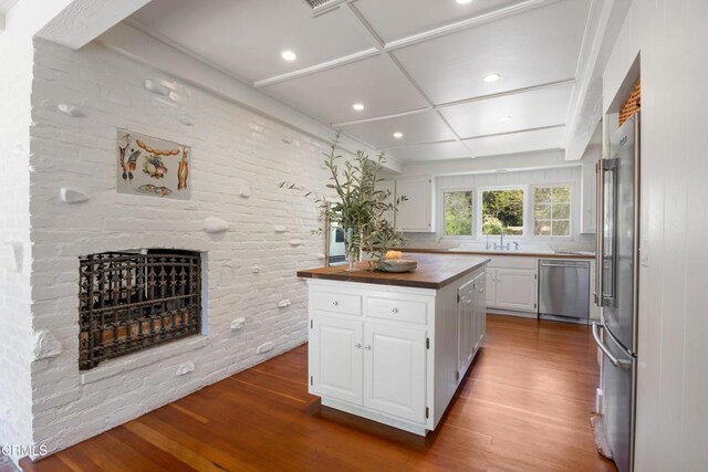 kitchen featuring butcher block countertops, dishwasher, wood-type flooring, white cabinets, and a kitchen island