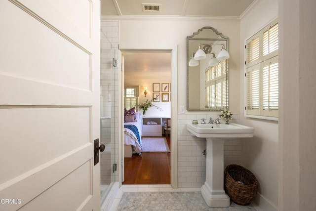 bathroom with tile patterned flooring, crown molding, and tile walls