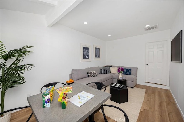 living room with beamed ceiling and light wood-type flooring