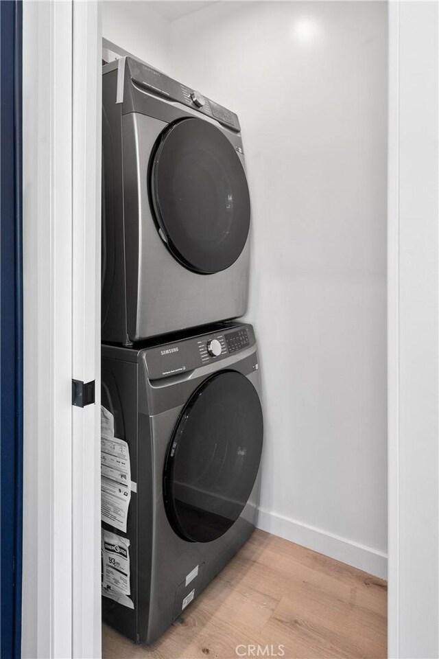 laundry room with stacked washer / drying machine and hardwood / wood-style flooring