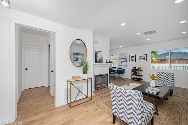 living room with light hardwood / wood-style floors and a brick fireplace