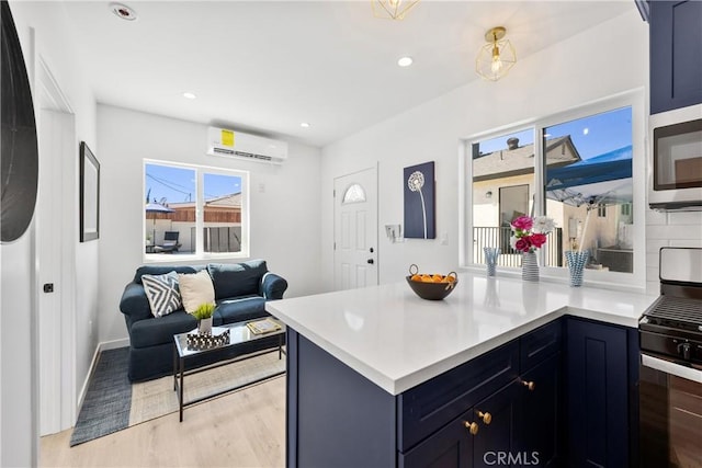 kitchen featuring gas range, plenty of natural light, a wall mounted AC, and light hardwood / wood-style flooring