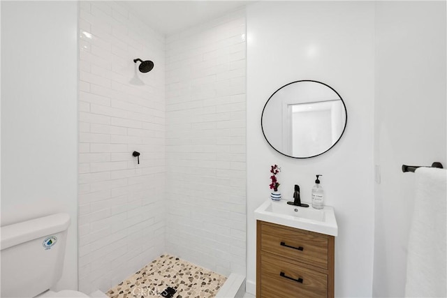 bathroom with vanity, toilet, and tiled shower